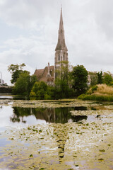Fototapeta na wymiar The profile of the church on its shore is reflected in a lake, in Copenhagen, Denmark.