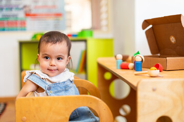 Toddler girl sitting on solid wooden montessori chair