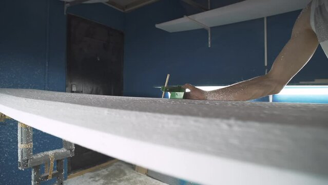 Male surfboard shaper making surfboard in his workshop. Hand shaping from blank.