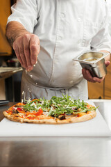 An Italian chef sprinkles freshly grated Parmesan cheese over a crispy pepperoni pizza, photo in motion