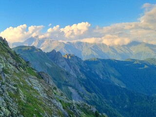 Amidst majestic mountains, vibrant meadows, and drifting clouds, a radiant rainbow graces the sky, painting a scene of natural wonder and beauty