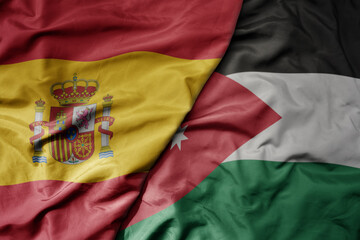 Fototapeta premium big waving national colorful flag of spain and national flag of jordan .
