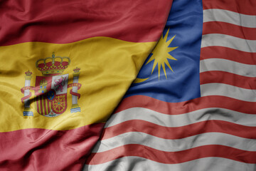 big waving national colorful flag of spain and national flag of malaysia .