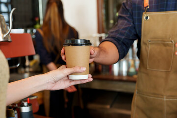 Portrait coffee mug, paper mug small size for drinking hot menu, with hand barista holding paper cup in hand, protruding from counter for customers order this cup coffee, customers reach out pick up.