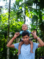 South asian young man with his little baby boy in a outdoor park 