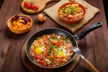Jewish food hot cholent and shakshuka in a frying pan on a set Shabbat table.