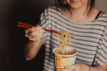 young woman eating instant noodles
