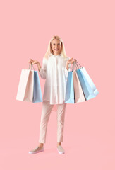 Mature woman with paper bags on pink background. Online shopping