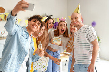 Group of young friends with Birthday cake taking selfie in kitchen