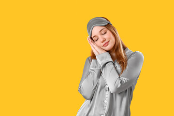 Young woman in pajamas on yellow background