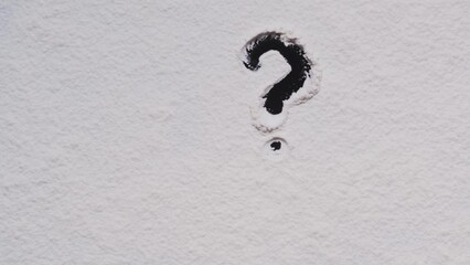 A man draws a question mark with his finger on a white background.