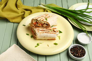 Plates of tasty shawarma with onion on green wooden background