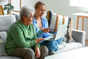 Young woman with her grandmother using laptop at home