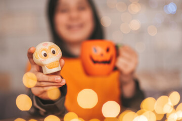 Portrait of candid authentic zoomer boy posing with jack lantern mug and sweets at halloween party