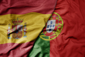 big waving national colorful flag of spain and national flag of portugal .