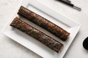 Plate with tasty maki rolls on light background, top view