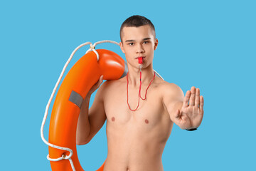 Male lifeguard with ring buoy and whistle showing stop gesture on blue background