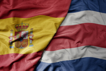 big waving national colorful flag of spain and national flag of costa rica .