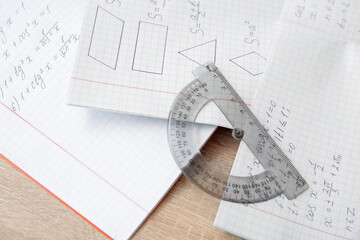 Open copybooks with math formulas and ruler on wooden table, closeup