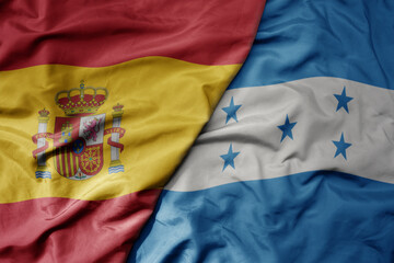 big waving national colorful flag of spain and national flag of honduras .