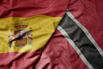 big waving national colorful flag of spain and national flag of trinidad and tobago .