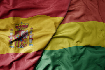 big waving national colorful flag of spain and national flag of bolivia .