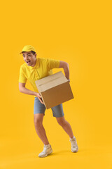 Male courier with parcel running on yellow background
