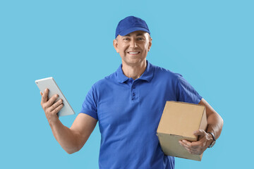 Mature courier with tablet computer and parcel on blue background