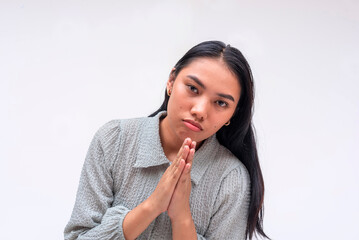 Fototapeta premium A young asian woman pleads for help, pressuring and making you feel guilty. Isolated on a white background.