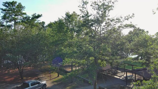 ascending aerial footage of a gorgeous summer landscape at Proctor Landing park with rippling lake water, lush green trees and grass with blue sky and clouds at Lake Acworth in Acworth Georgia USA