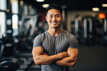 Fototapeta premium Smiling portrait of a young male asian fitness trainer instructor working in a gym