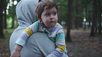 criminal portrait of a kidnapper with a child in his arms walks with his back to the camera in the woods close up