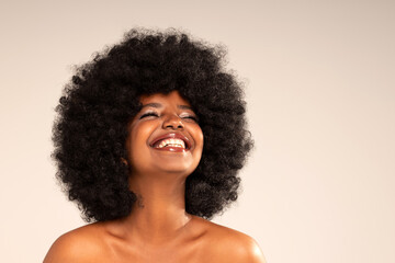 Studio portrait of young happy woman with afro hair and amazing toothy smile . Joyful girl posing...