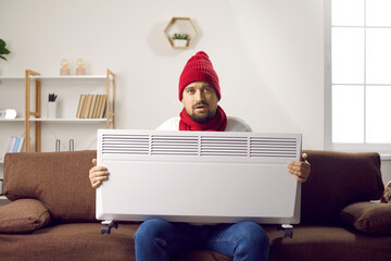 Man freezing and trying to warm up when it's very cold in the house in winter. Man wearing a warm...