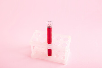 Test tube with sample in stand on pink background