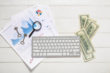 Keyboard with diagrams, keys, magnifier and money on white wooden background. Concept of buying real estate