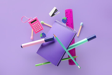 Different flying stationery on lilac background
