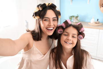 Little girl with her mother curling hair in bathroom, closeup