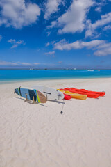 Fototapeta na wymiar Beach coast in Maldives sea. Sup boards, kayaks close zo calm ocean bay water. Outdoor sport recreational equipment, fun wellbeing water activity. Sunshine, blue seascape sky, tropical resort