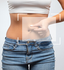 Girl pulls the skin on the abdomen, showing the body fat in the abdominal area and sides. Treatment and disposal of excess weight, the deposition of subcutaneous fat.