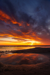 Fototapeta premium sunset sky with reflections in water, sunlight and colored orange clouds. Magnificent view of the sea and sun in evening. travel and freedom, meditation, poster. amazing sunset light on ocean