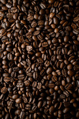 Overhead view of dark brown fresh roasted coffee beans background. Copy space