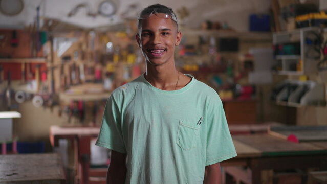 Portrait of a young Brazilian Black Carpenter standing in Workshop smiling at workshop. Happy diverse apprentice of local business, job occupation concept