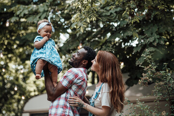 Portrait of candid friendly happy interracial family hold swarthy baby in your arms at camper park