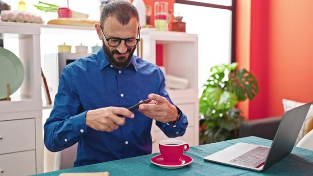 Young hispanic man make photo to cup of coffee smiling at dinning room