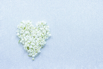 a heart made of lily-of-the-valley flowers. background with lily of the valley flowers top view. lilies of the valley in the form of a heart and a copy of the space.