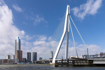 Rotterdam, the Netherlands-February 2023  Panoramic view over Maas river with Erasmus suspension bridge and downtown with skyscrapers Zalmhaven Tower and Cooltower against a white clouded blue sky