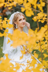 Portrait of a beautiful smiling bride. Autumn portrait of the bride. Yellow autumn leaves