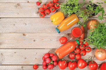 Tomato and carrot juices in bottles with spices and herbs and ingredients on a wooden table. Detox...