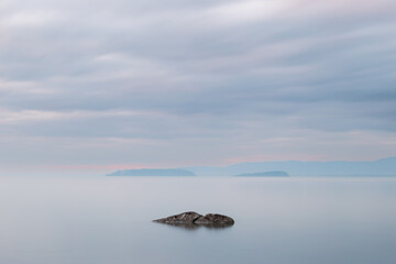 Long exposure view of a rock in Trasimeno lake Umbria, with islands in the background and moody sky - 639393873